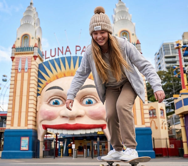 teenager skateboarding in front of Luna Park Australia with a large smiling face sculpture in the background.